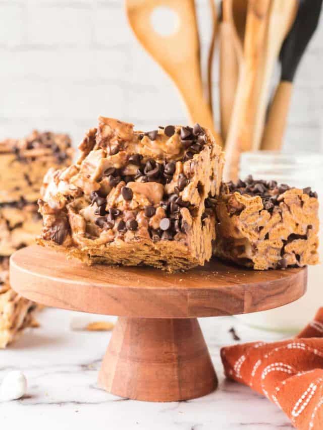 A wooden cake pedestal with sliced s'mores bars displayed on top.