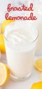 A cup of frosted lemonade in a glass with lemons scattered around the glass.