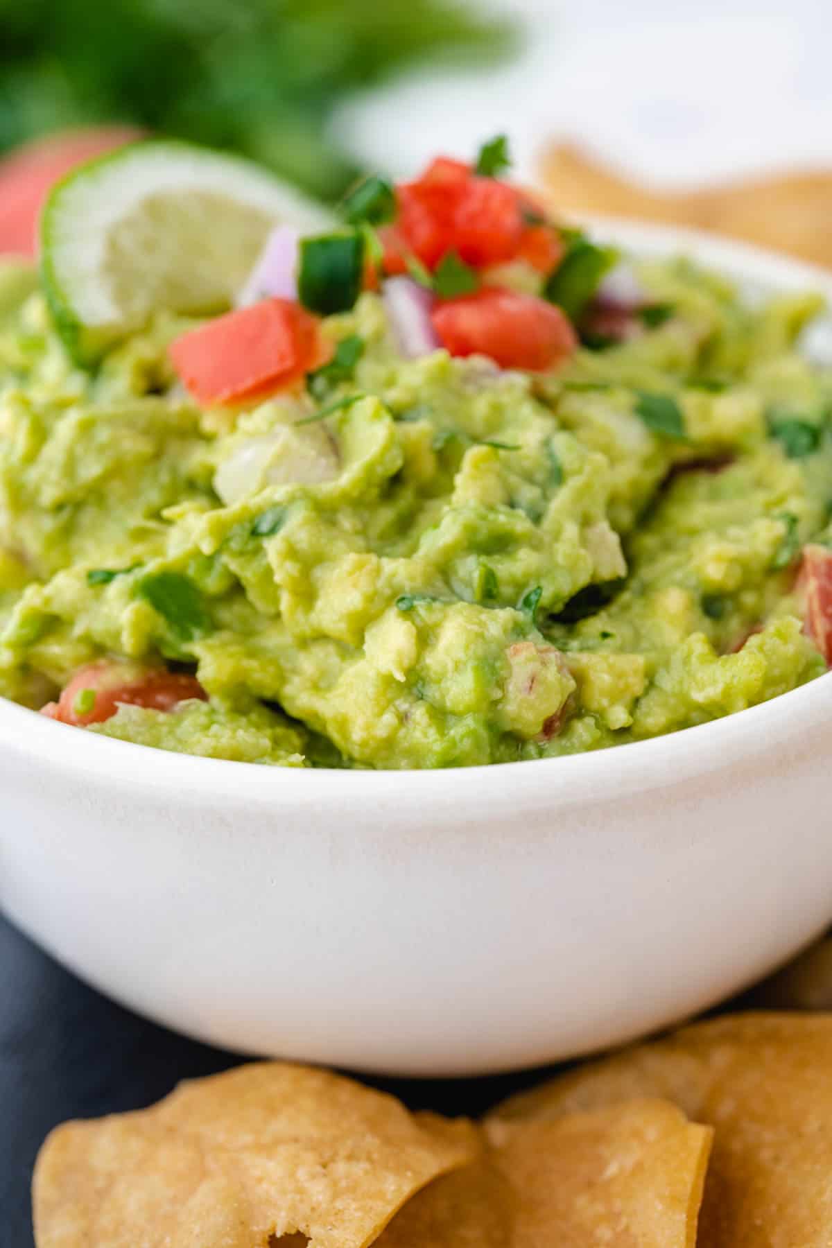 An up-close image of a white bowl filled with chunky guacamole.