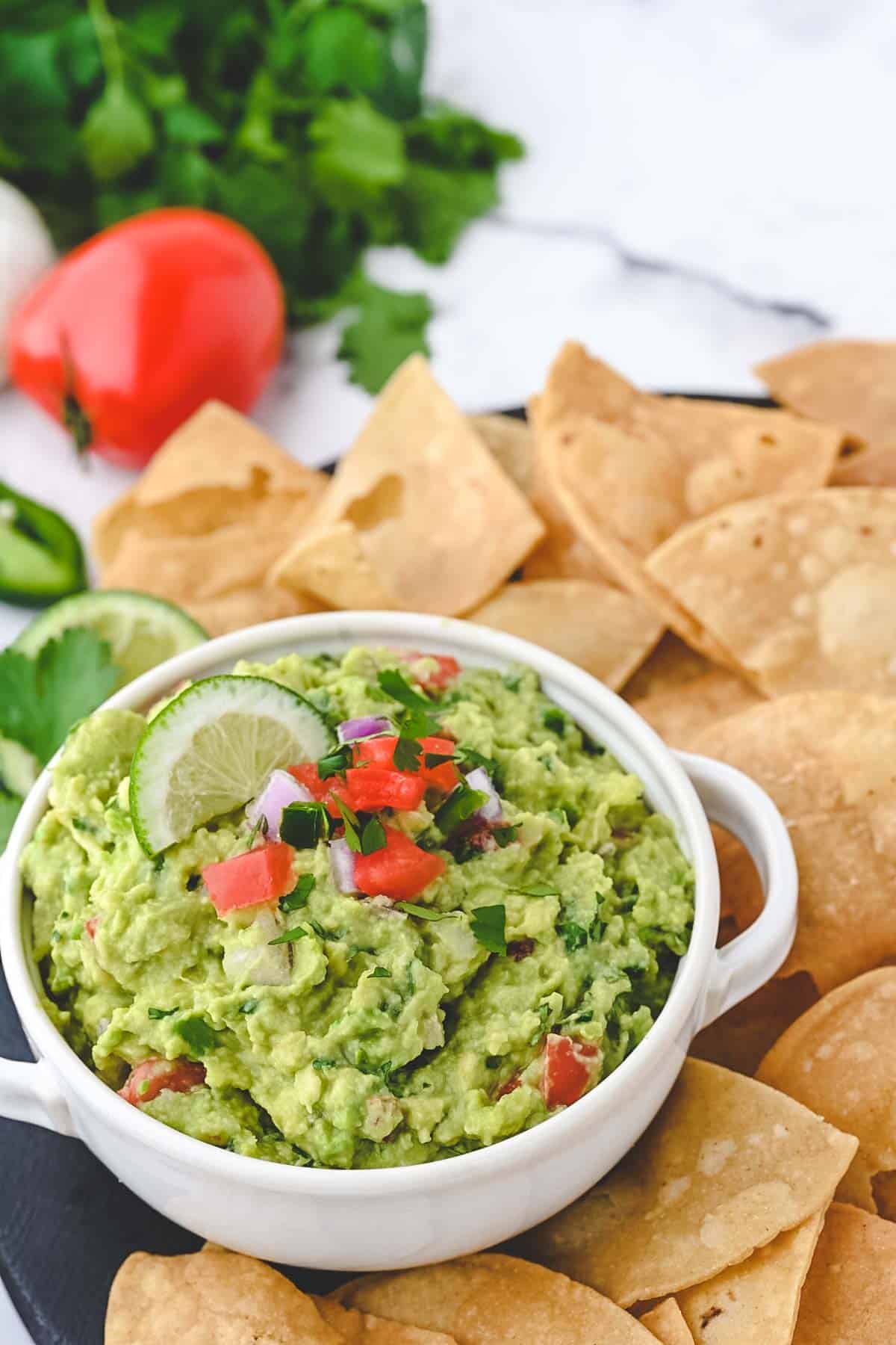 A bowl of fresh guacamole surrounded by homemade tortilla chips.