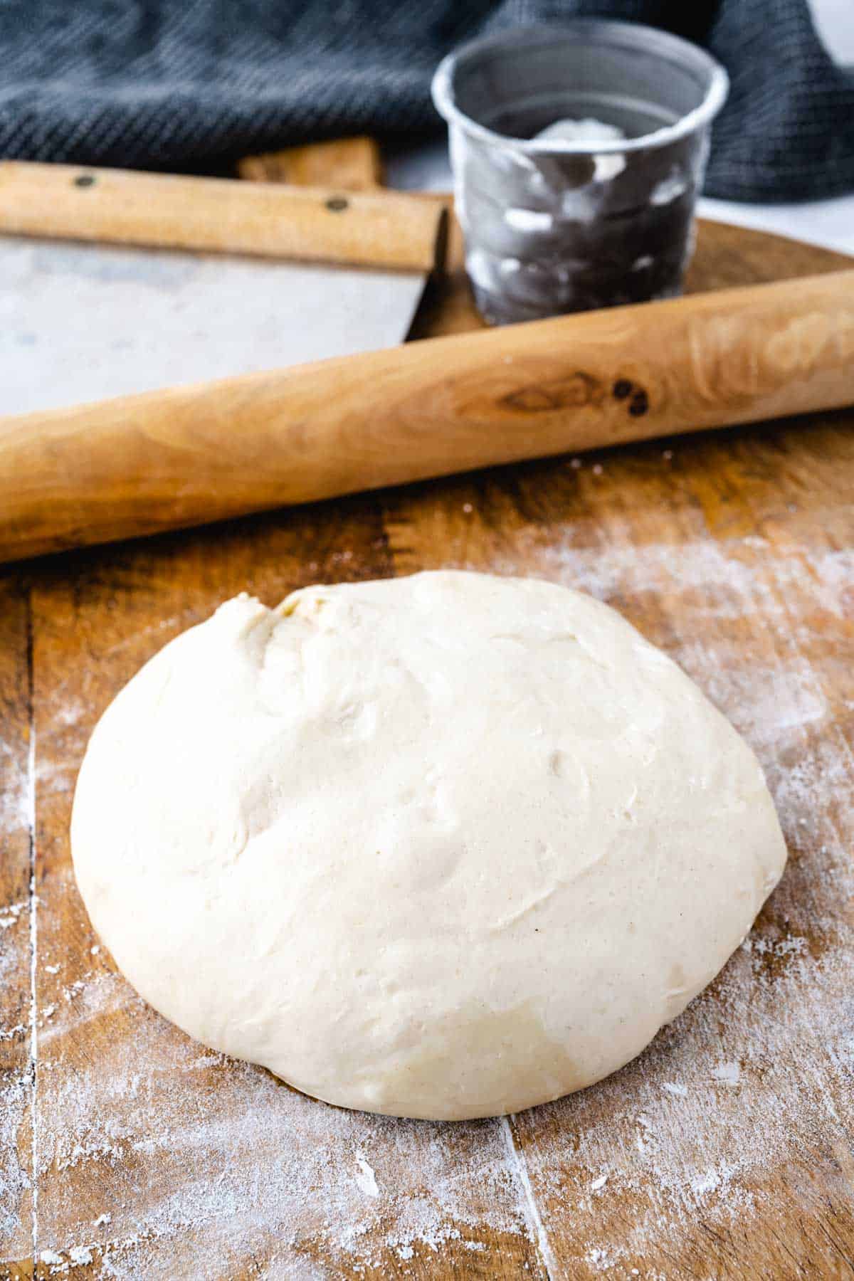 A close-up shot of a floured wooden board with 10-minute pizza dough ball ready to use.