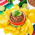 A bowl of restaurant style salsa surrounded by tortilla chips.