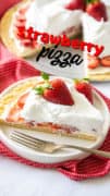 A white plate filled with strawberry pizza with a whole dessert pizza in the background.