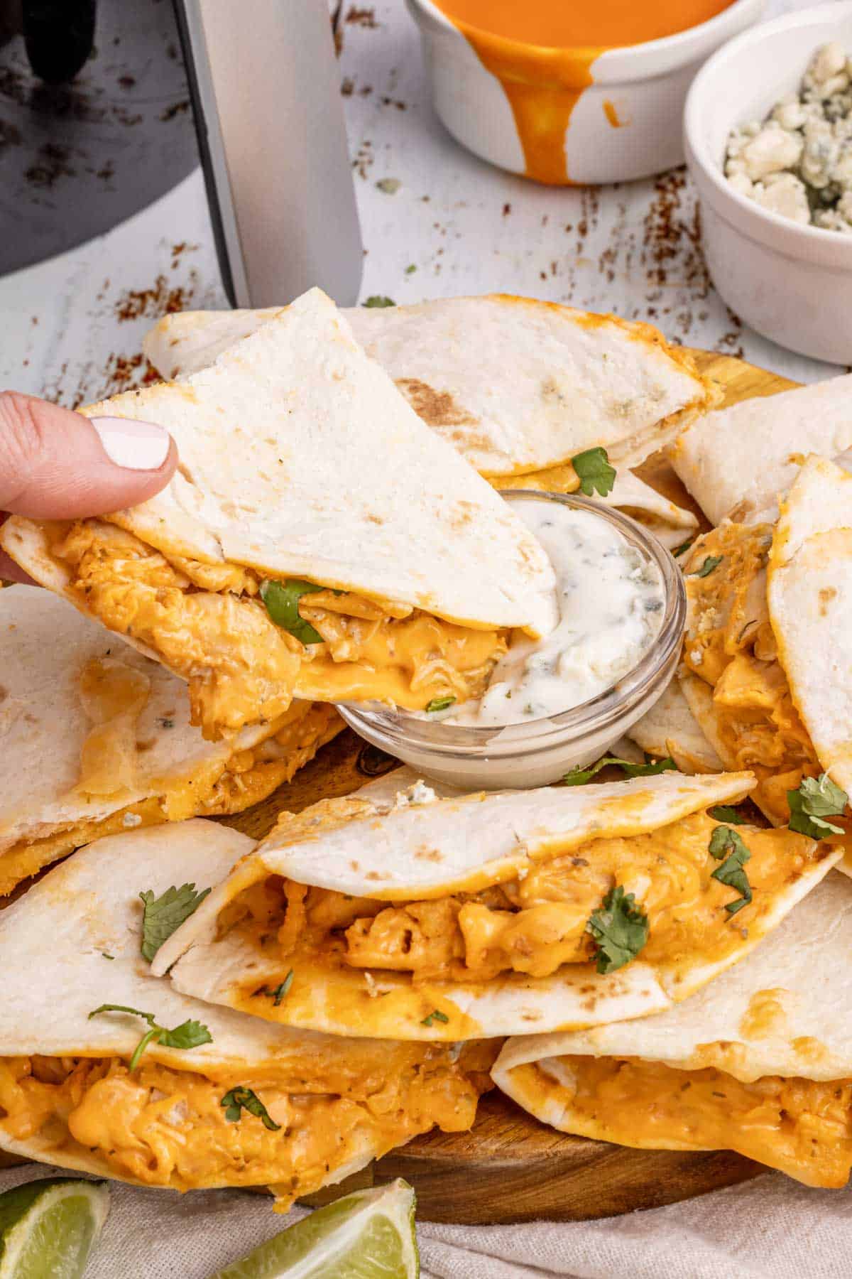 A hand dipping a quesadilla into ranch dressing.