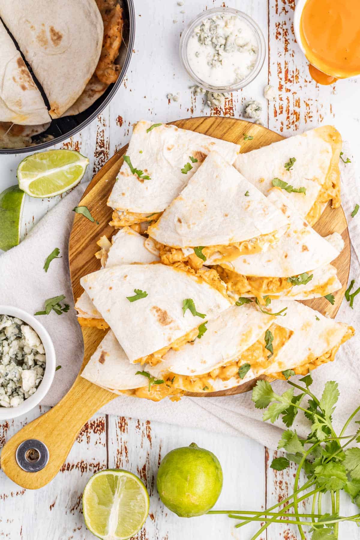 A wooden tray filled with buffalo chicken quesadillas.