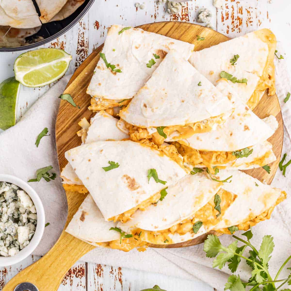 A wooden tray filled with buffalo chicken quesadillas.