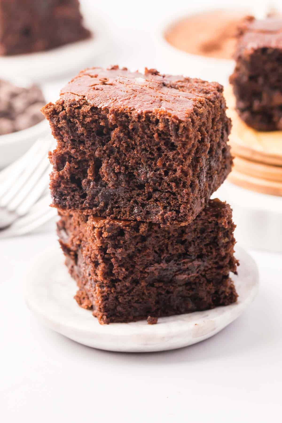 Brownies stacked two high on a white wood plate.