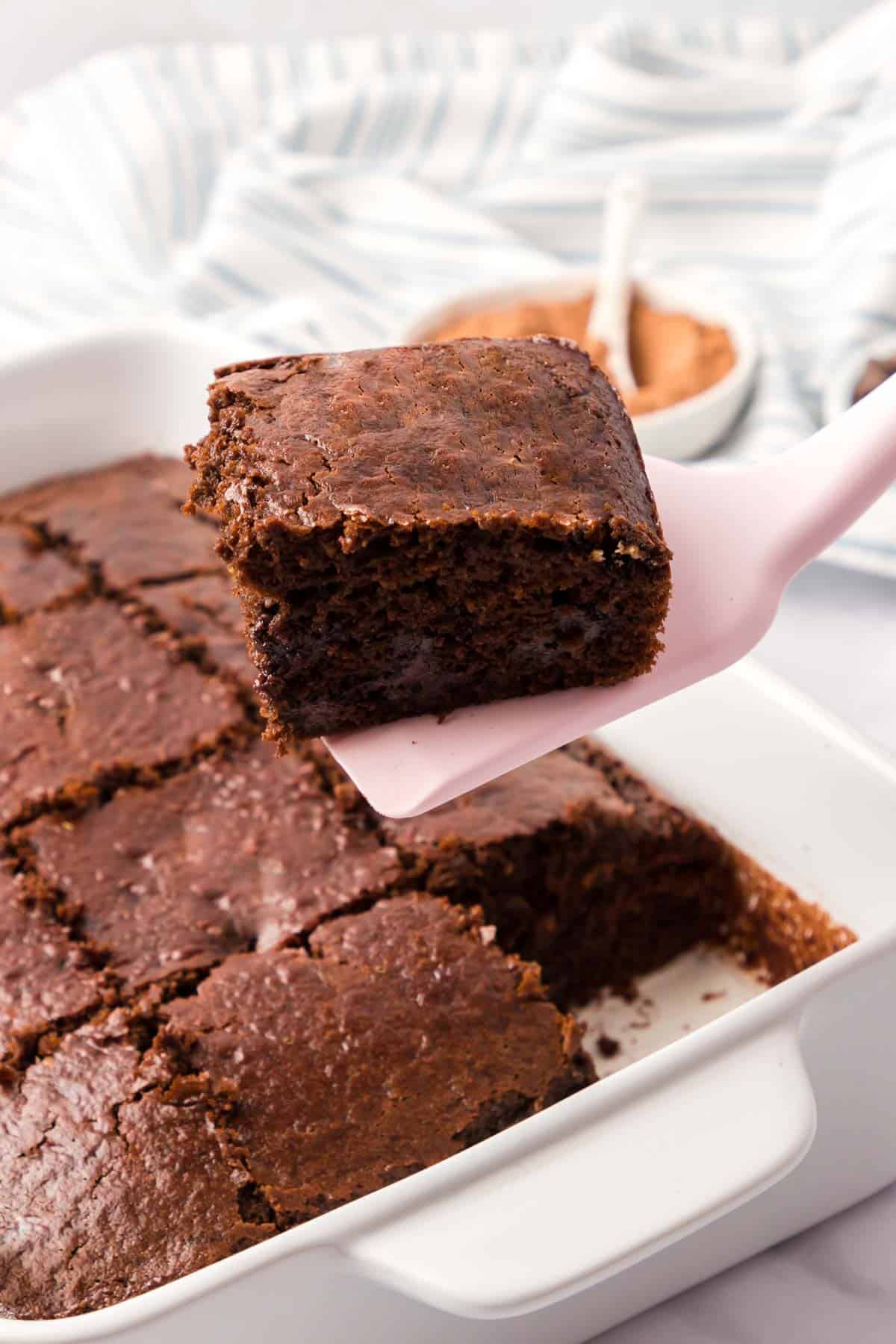 A pan of brownies with a sliced brownie removed with a pink spatuala.