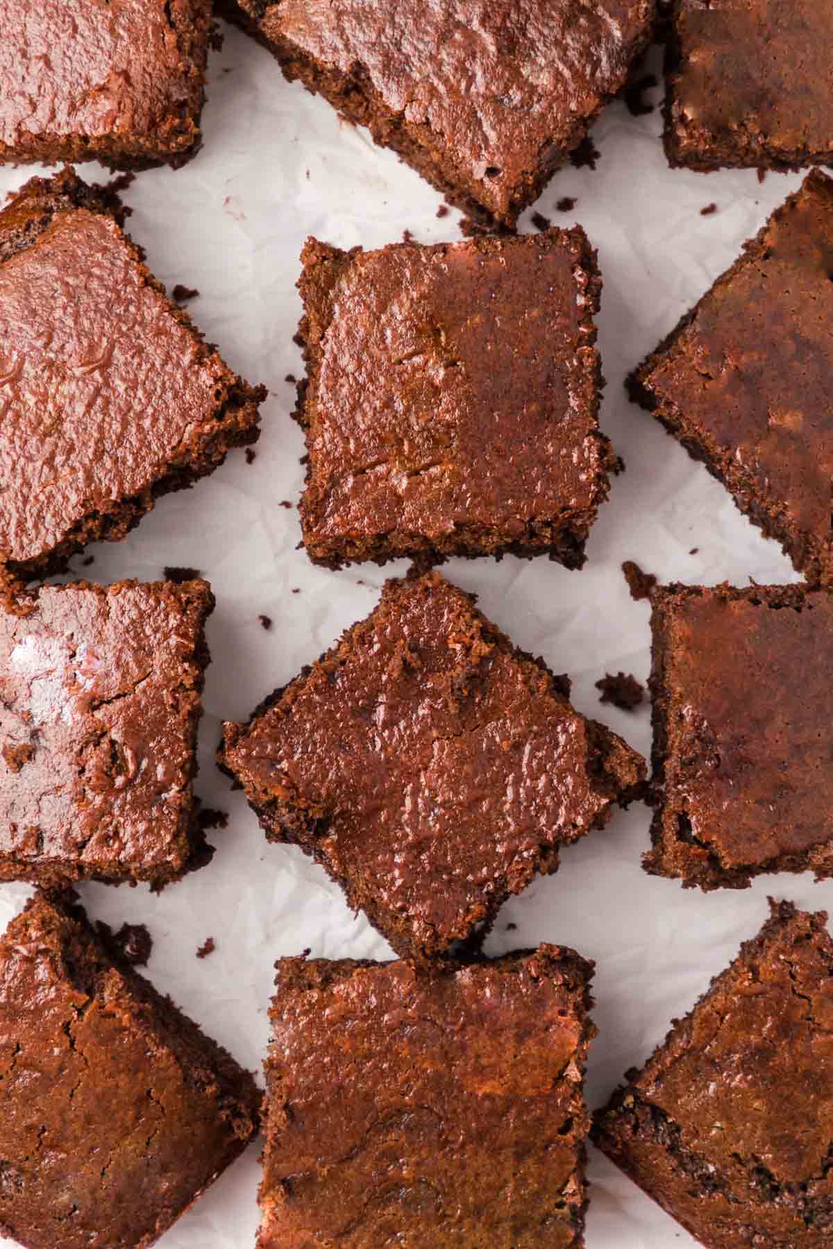 Cut cake brownies slices laid out on parchment paper.