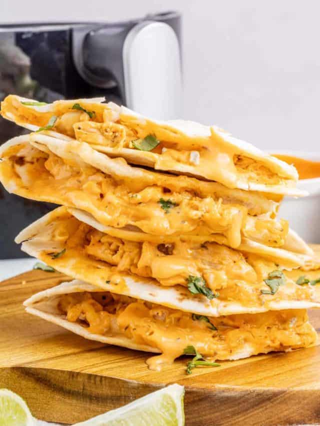 Quesadilla triangles stacked on top of each other with gooey cheese and buffalo sauce oozing out.