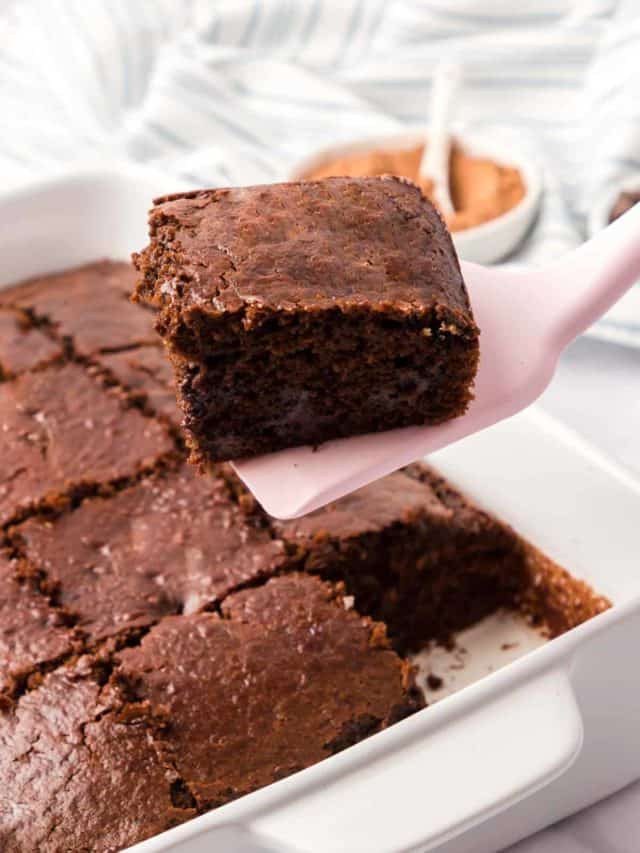 A pan of brownies with a sliced brownie removed with a pink spatuala.