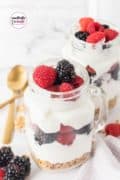 A Pinterest image with text and two jars of yogurt parfaits with raspberries and blackberries.