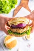 Hands holding a juicy good ground chicken burger pinterest image pin 4.