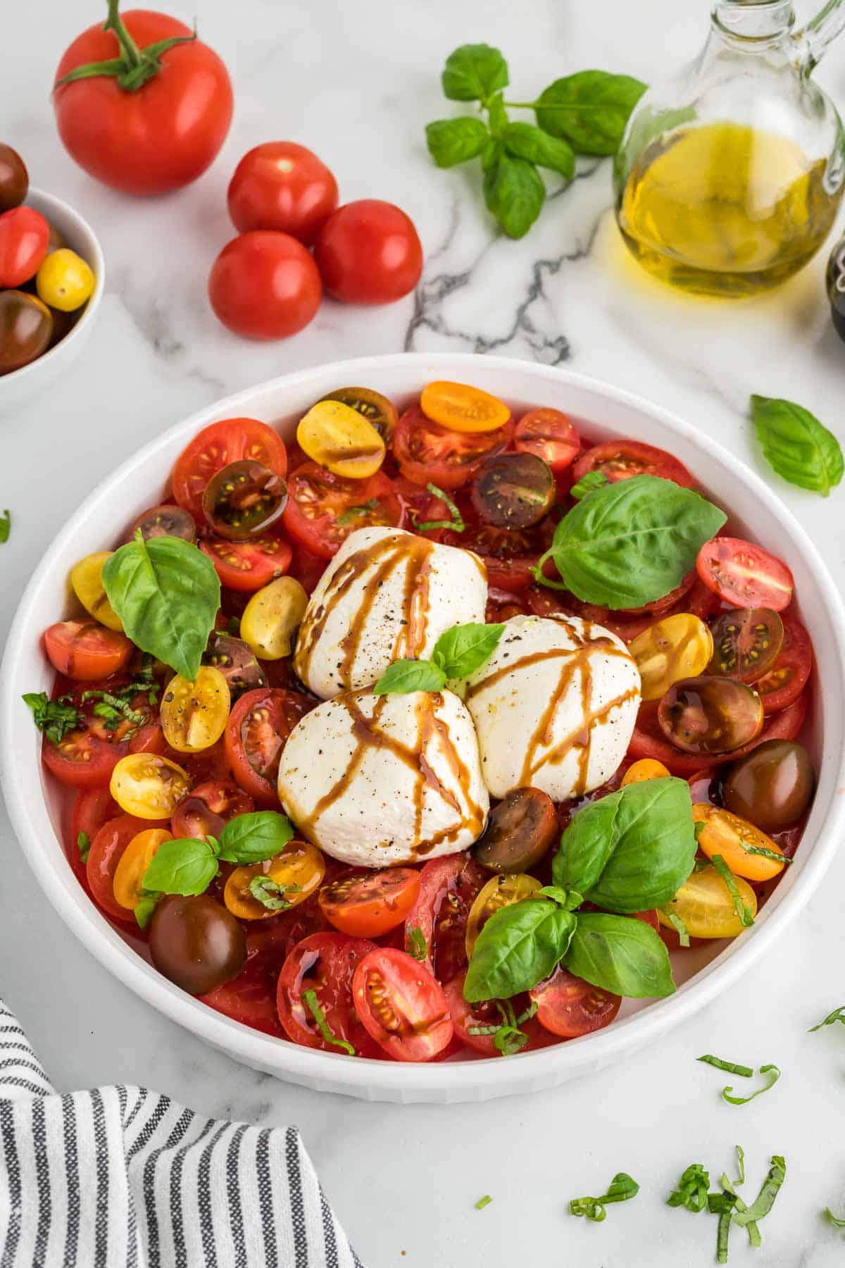 A Burrata Caprese Salad garnished with basil and drizzled with balsamic glaze.