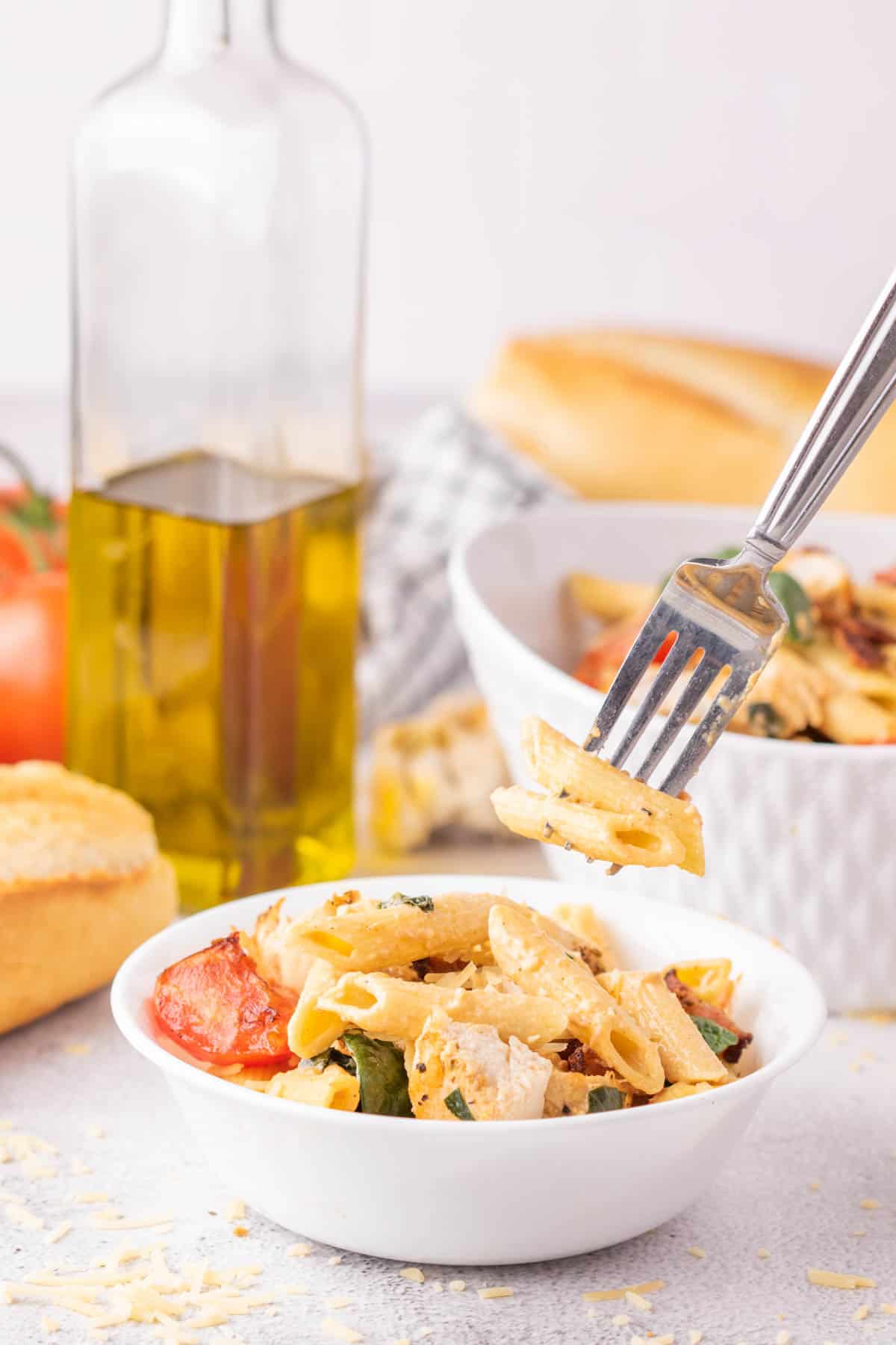 A form removing a bit of pasta from a white bowl.