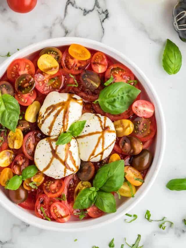 A Burrata Caprese Salad garnished with basil and drizzled with balsamic glaze.