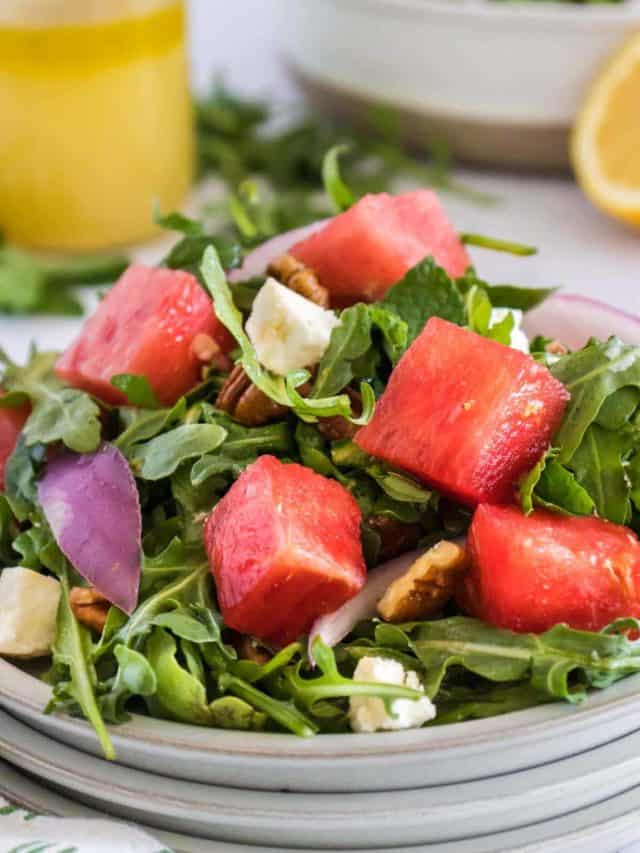 An arugula salad with watermelon and feta cheese on a plate.