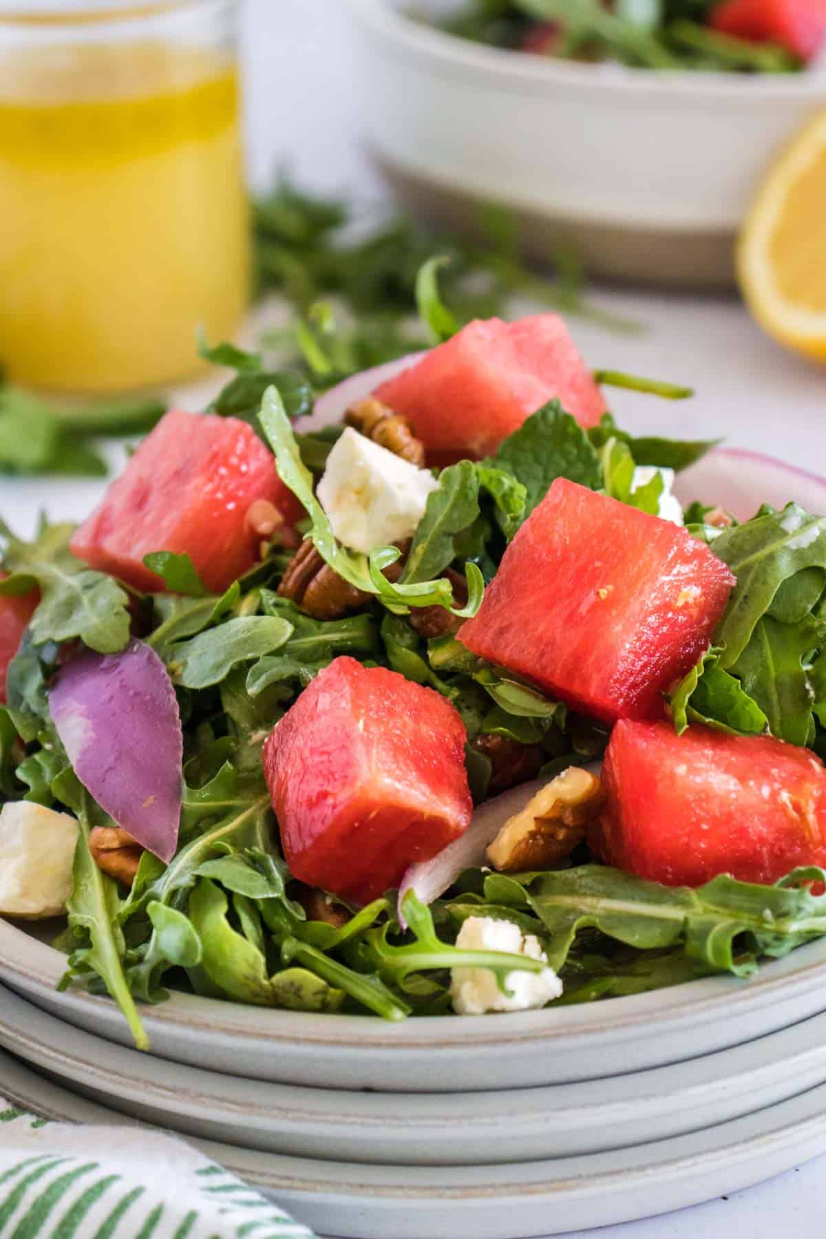 An arugula salad with watermelon and feta cheese on a plate.