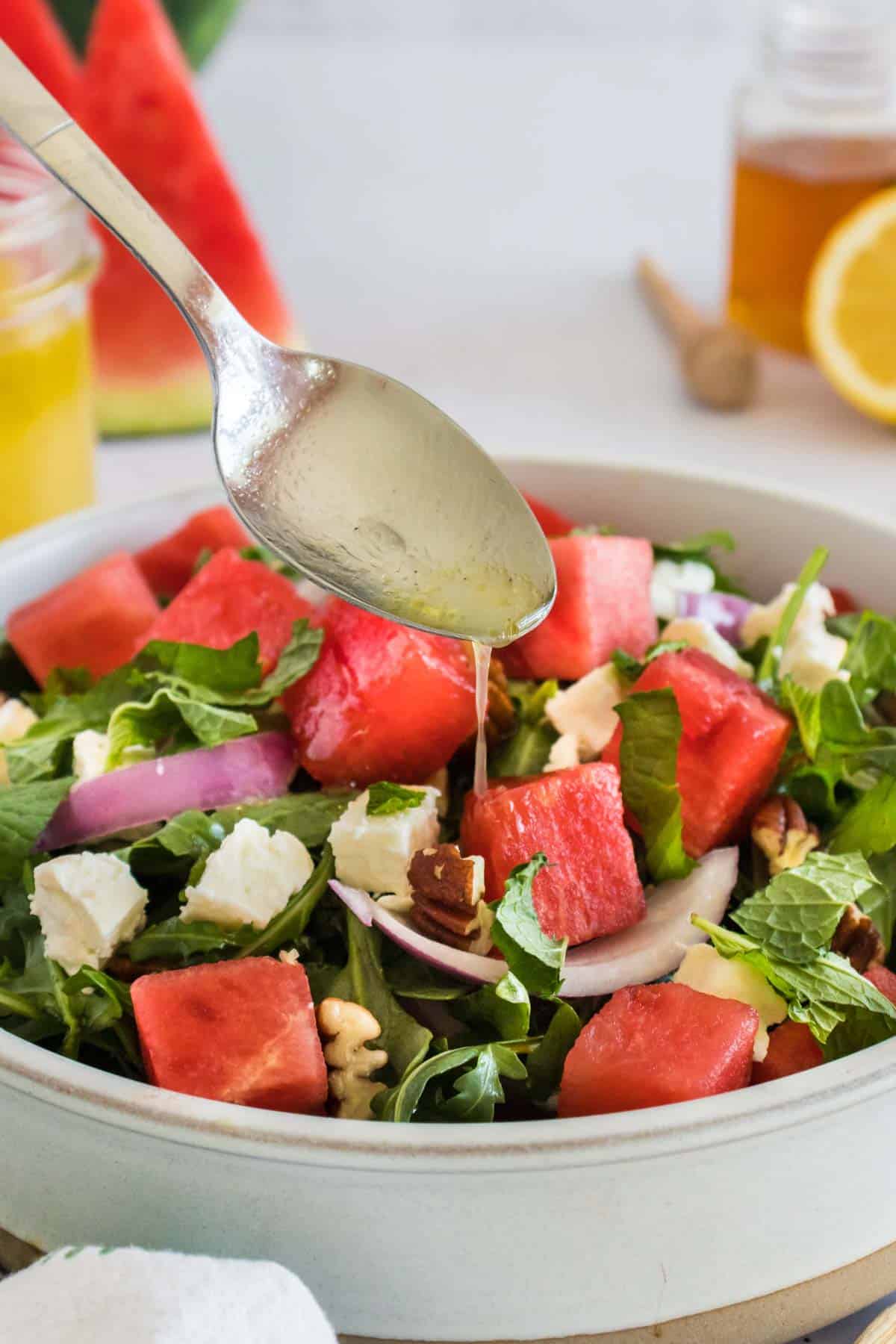 Lemon vinaigrette dressing being drizzled over a salad.