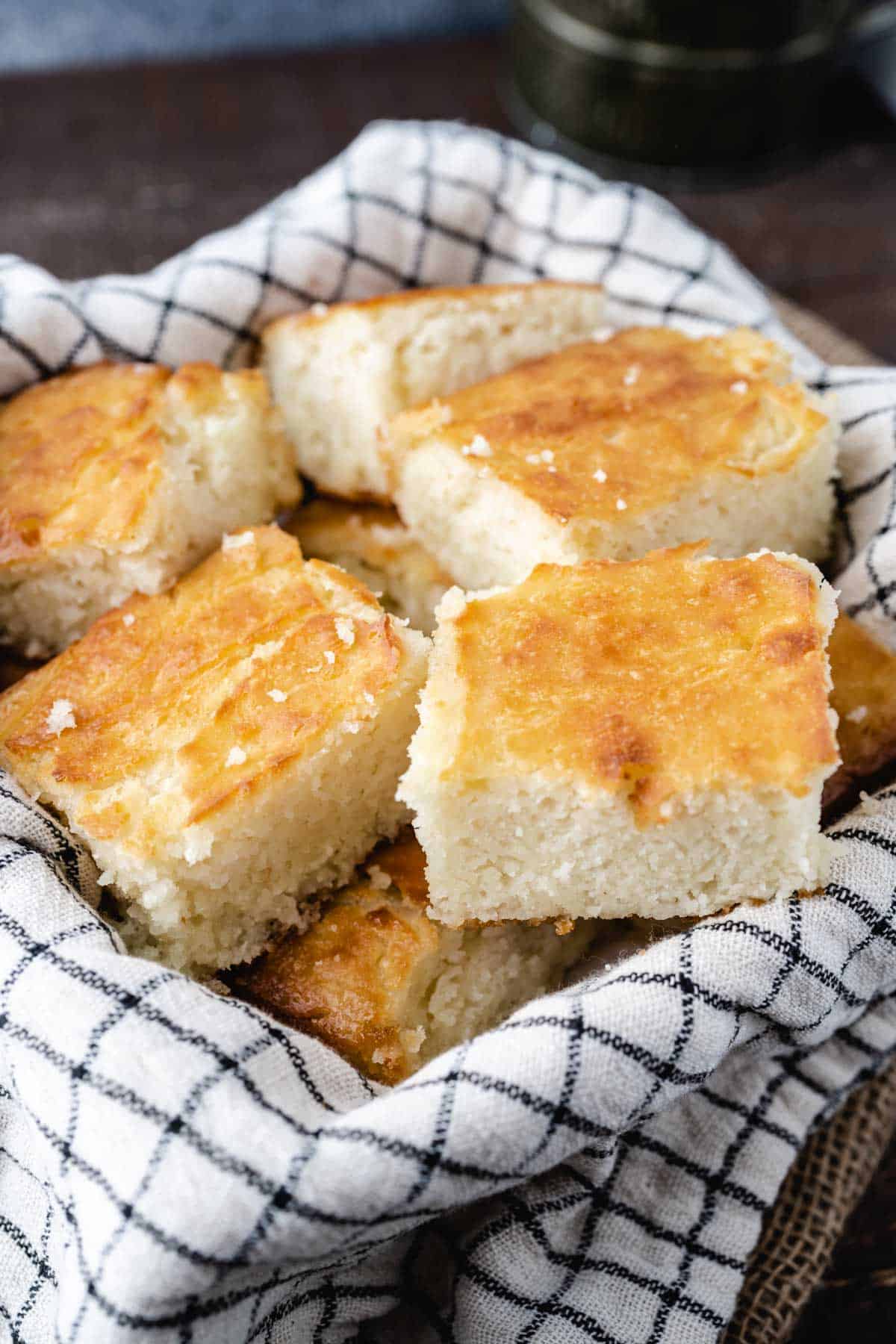 A basket with a tea towel full of sliced butter dip biscuits.