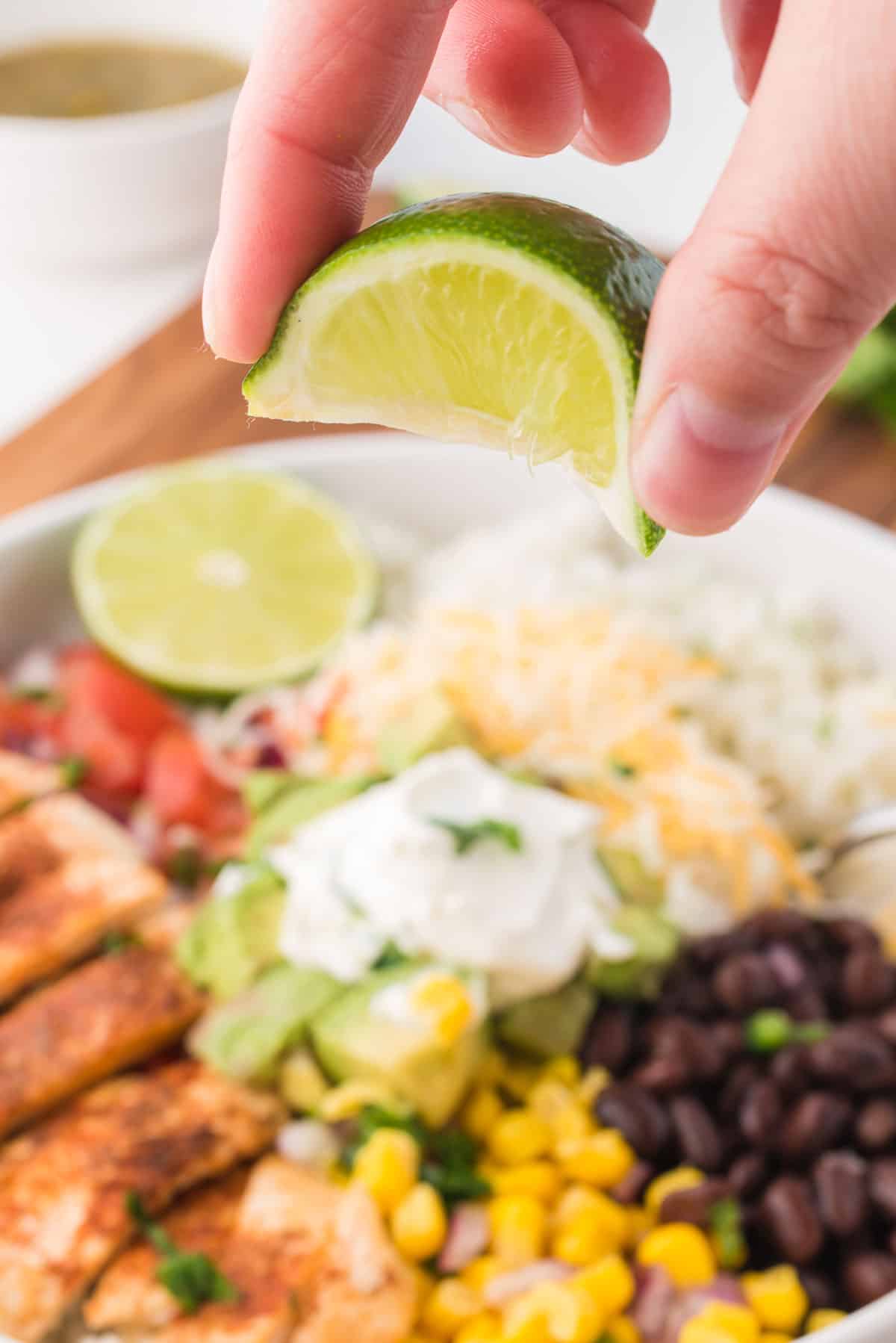 Squeezing a lime wedge over a Mexican chicken burrito bowl.