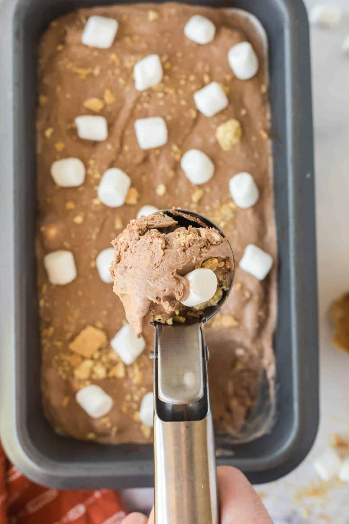 A container of S'more Ice Cream with a scoop being removed with an ice cream scooper.