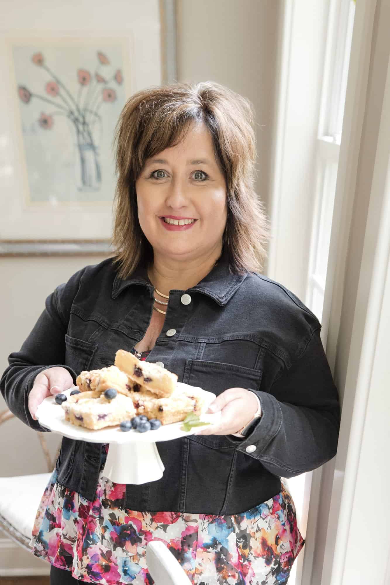 Author Nikki Lee serving a tray of blueberry bars.