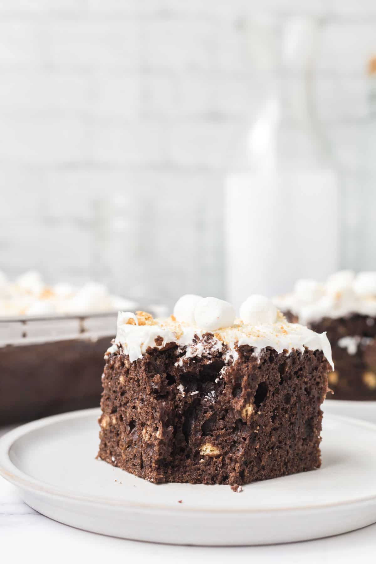 A slice of easy s'mores cake with a bite removed from the cake on a white plate.