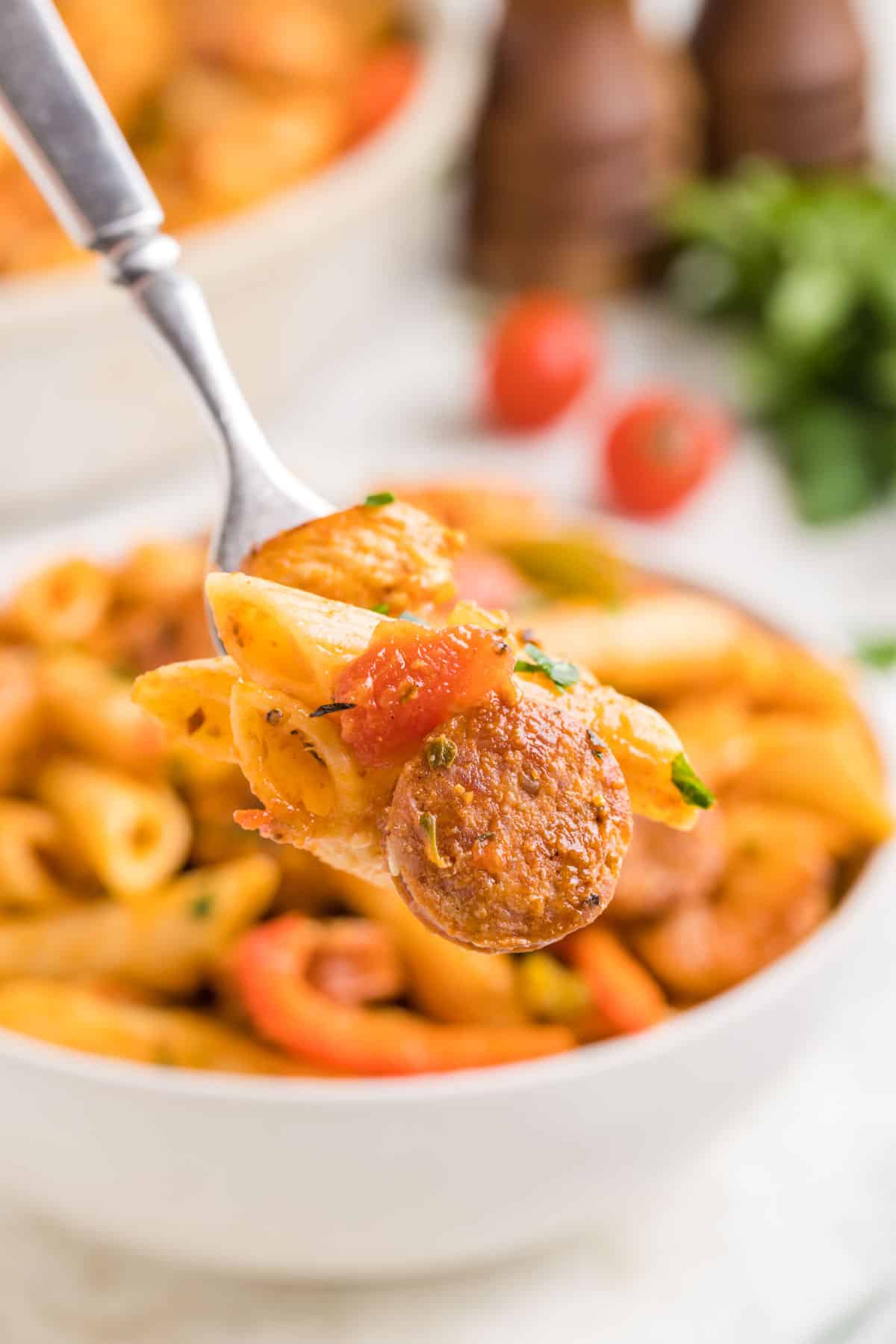 A fork removing a bite of jambalaya pasta from a white bowl.