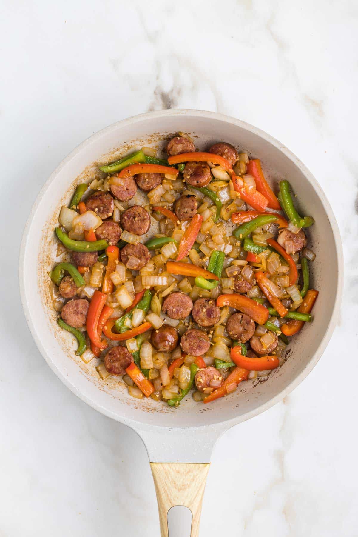 Sautéing onions, peppers, garlic in pan with sausage.