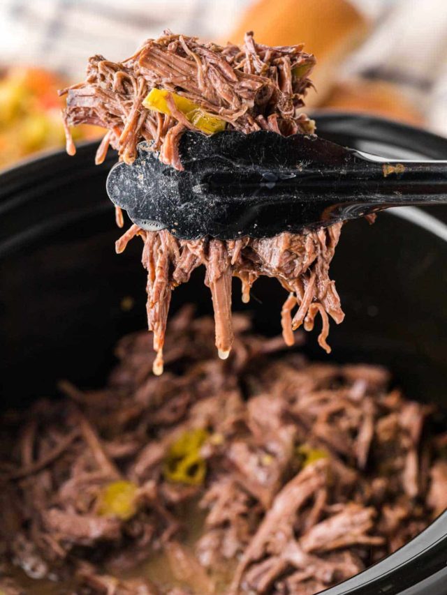 Tongs removing beef from the slow cooker.