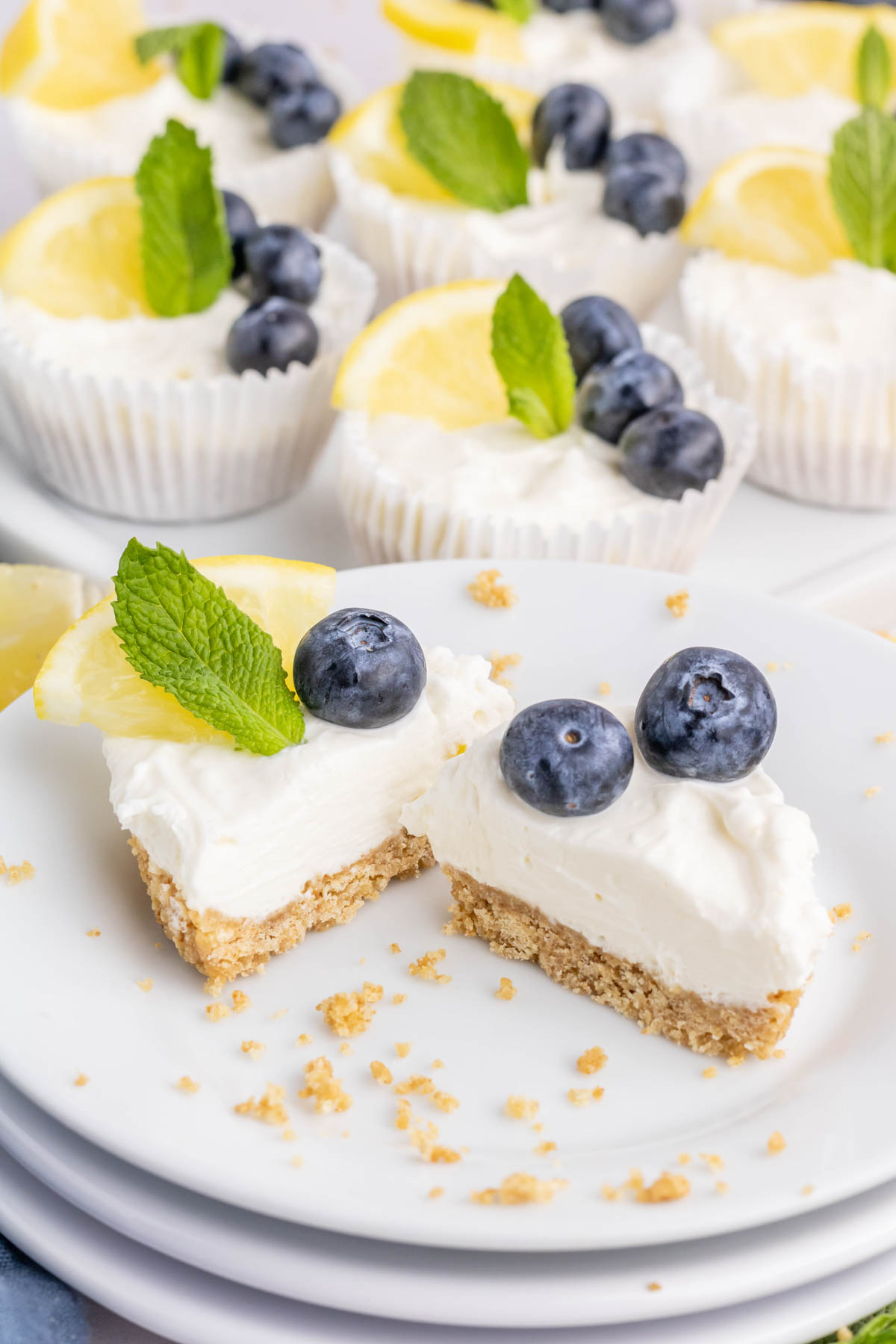 A mini lemon cheesecake sliced in half on a white plate.