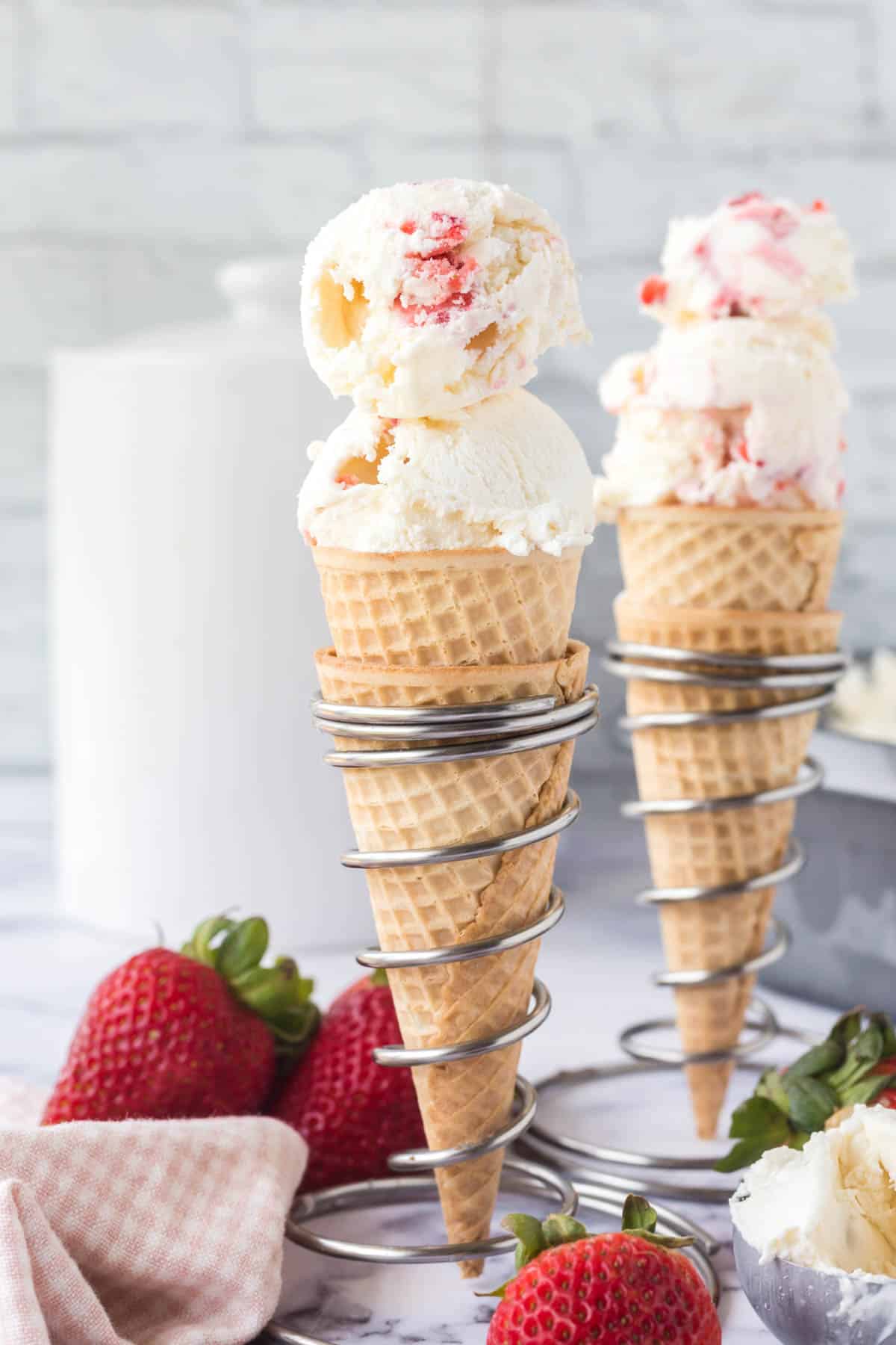 Two ice cream cones filled with strawberry ice cream.