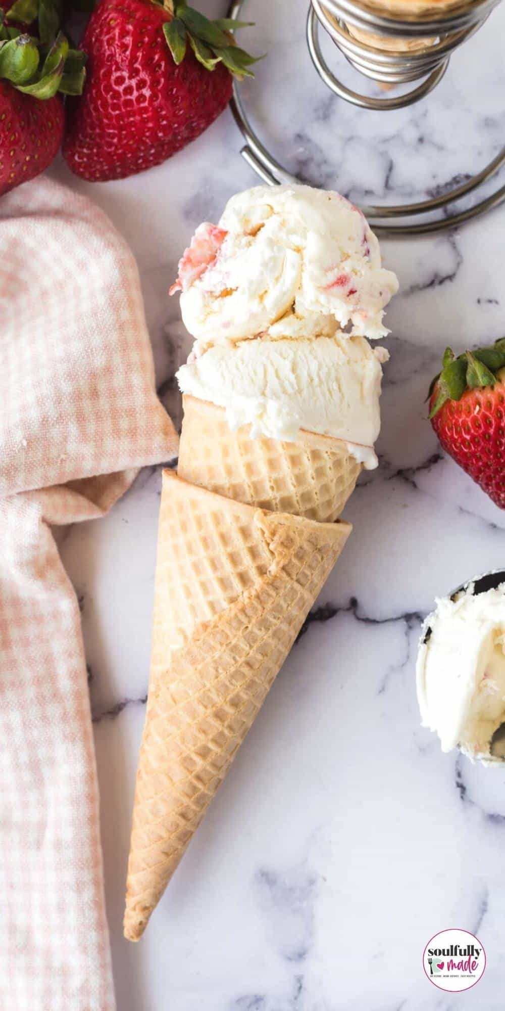 A waffle cone filled with two scoops of strawberry ice cream.