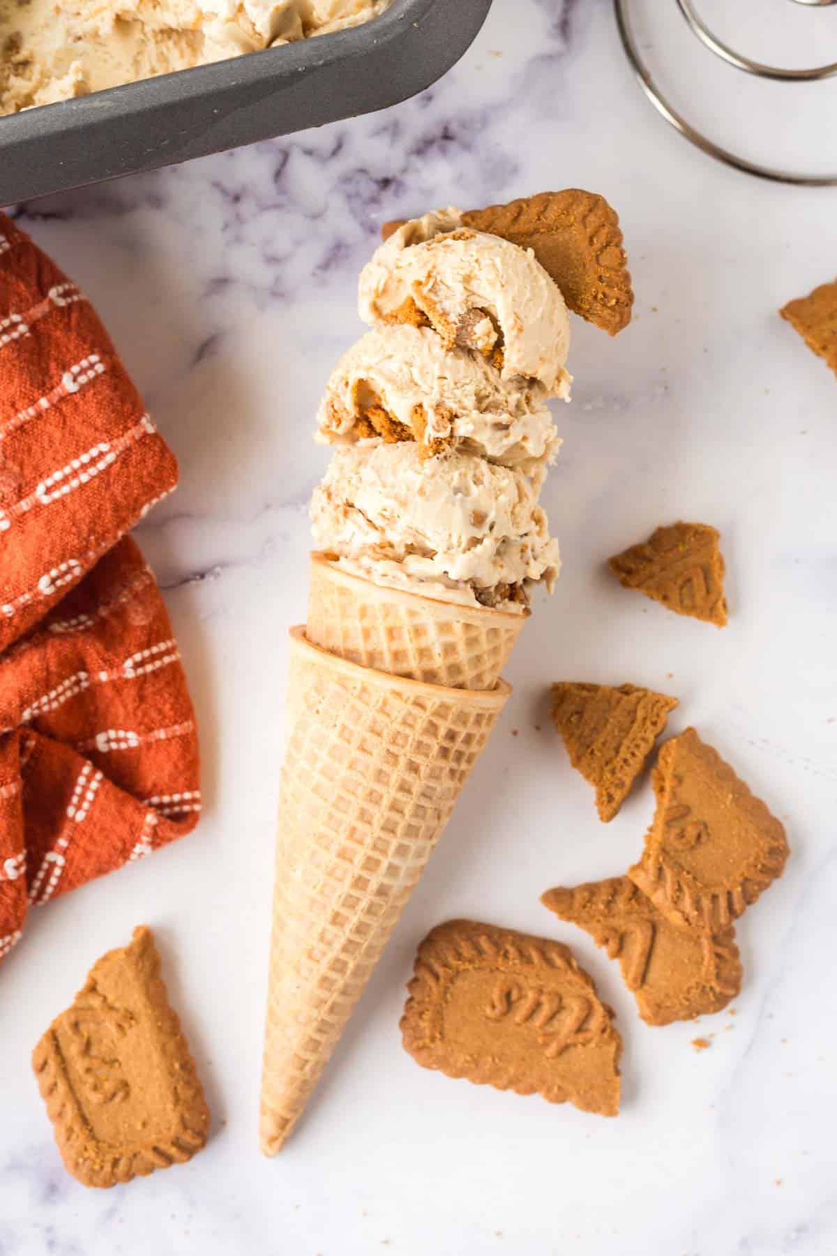 A waffle cone filled with no-churn biscoff ice cream on a marble table background.