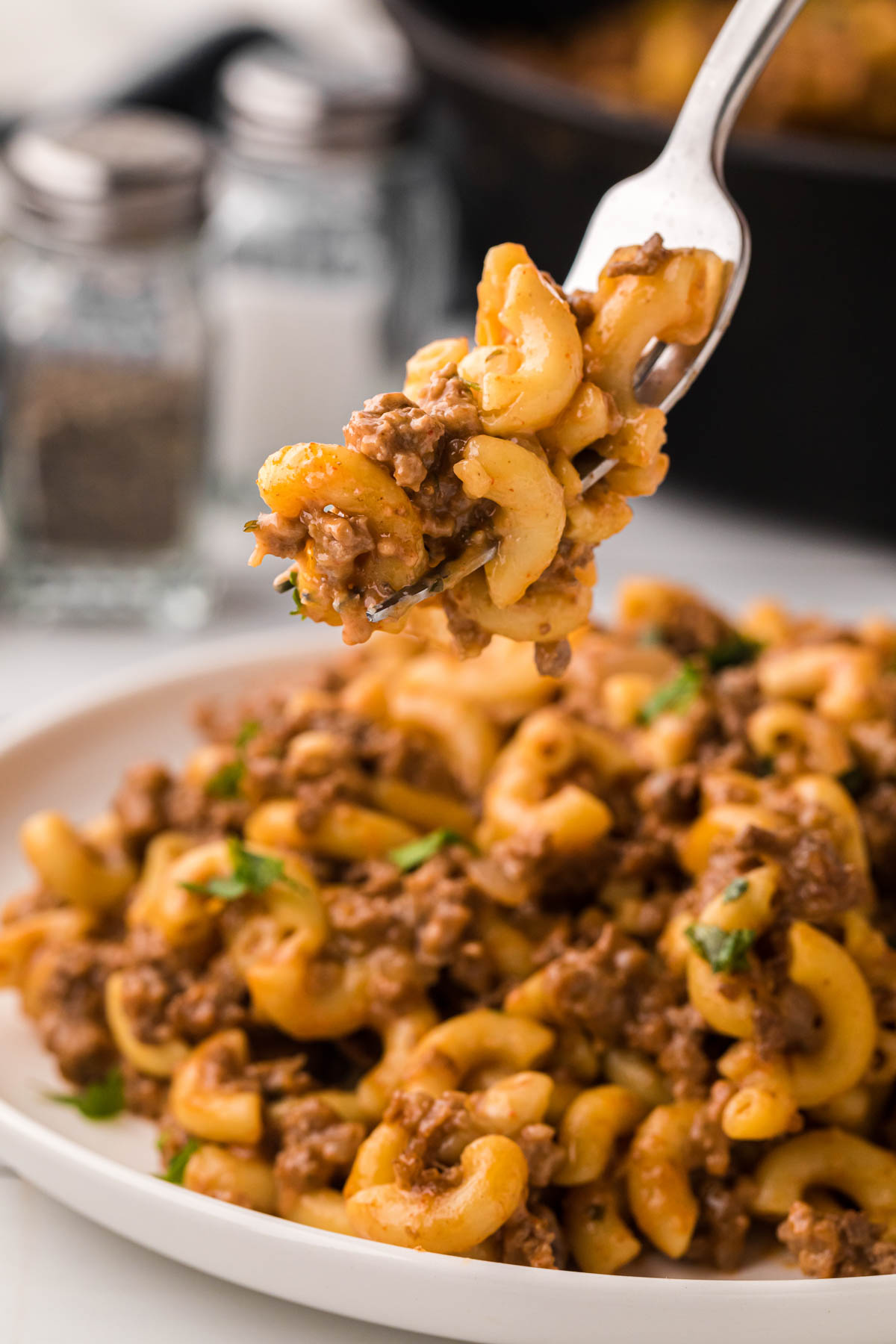 A fork removing a bite of hamburger helper from the plate.