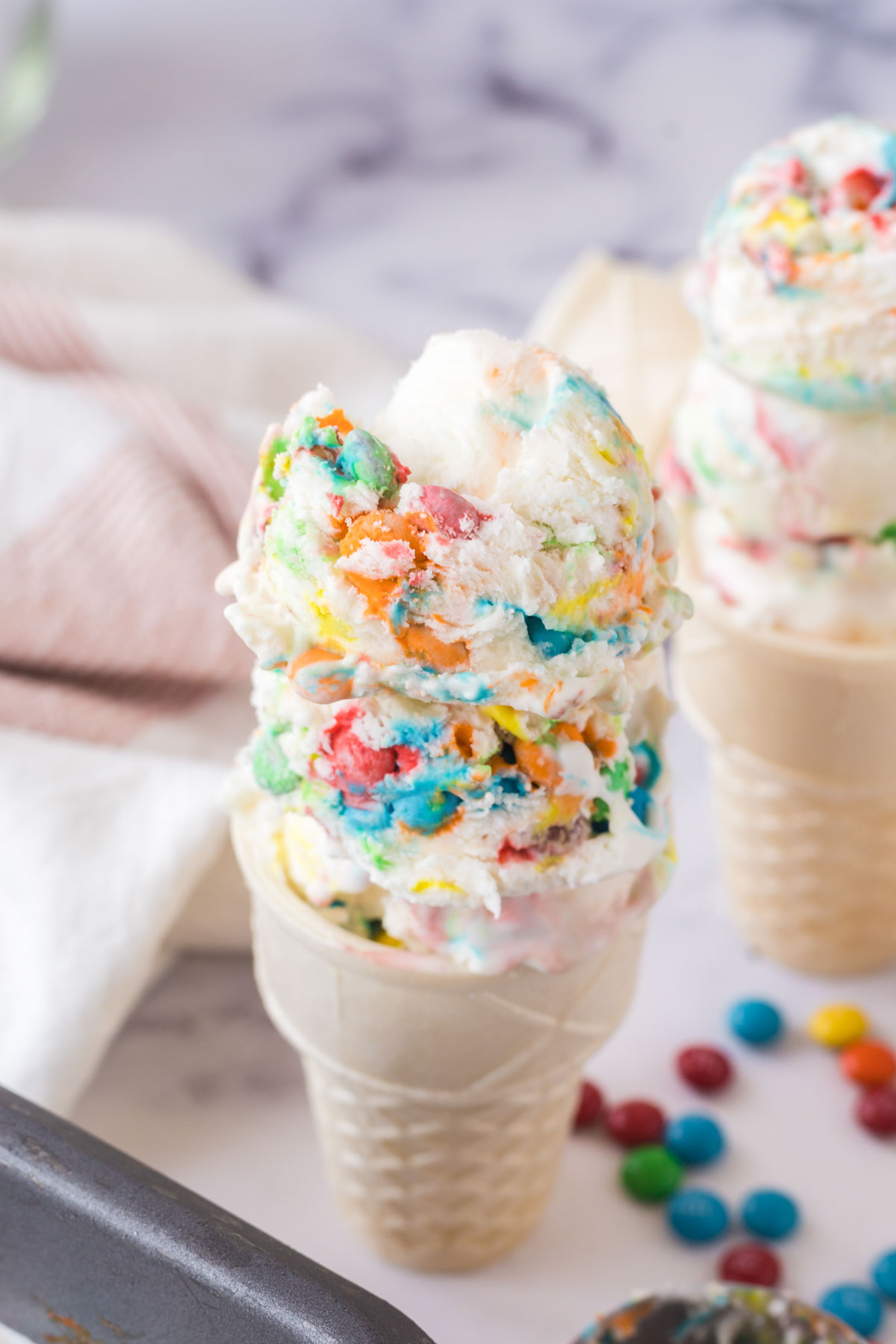 Two sugar cones filled with no-churn M&M ice cream.