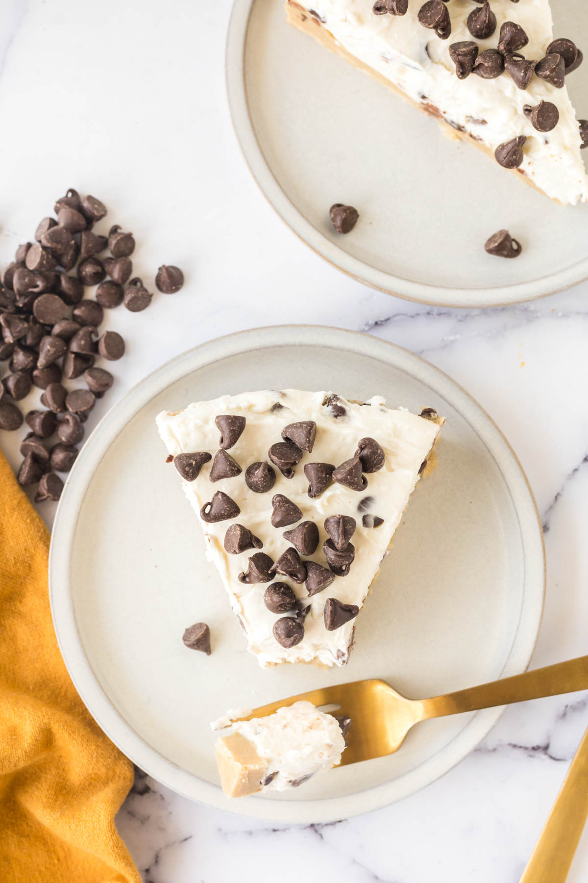 A slice of no-bake cookie dough cheesecake on a white plate with a bite removed with a fork.