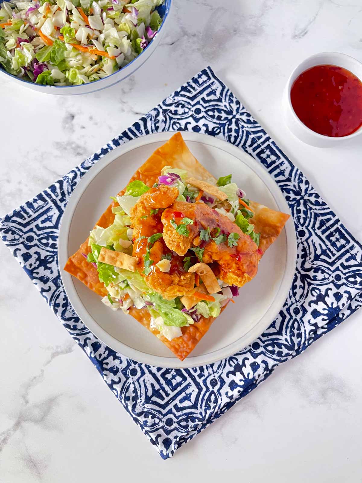 An overhead view of Asian Chicken wonton tostada set on a white plate.