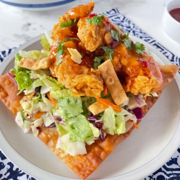 Asian Crunch Chicken Salad on a egg roll wrapper base set on a white plate on top of a blue and white placemat.
