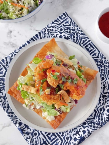 An overhead view of Asian Chicken wonton tostada set on a white plate.