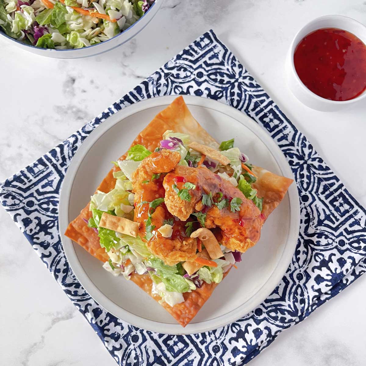 An overhead view of Asian Chicken wonton tostada set on a white plate.