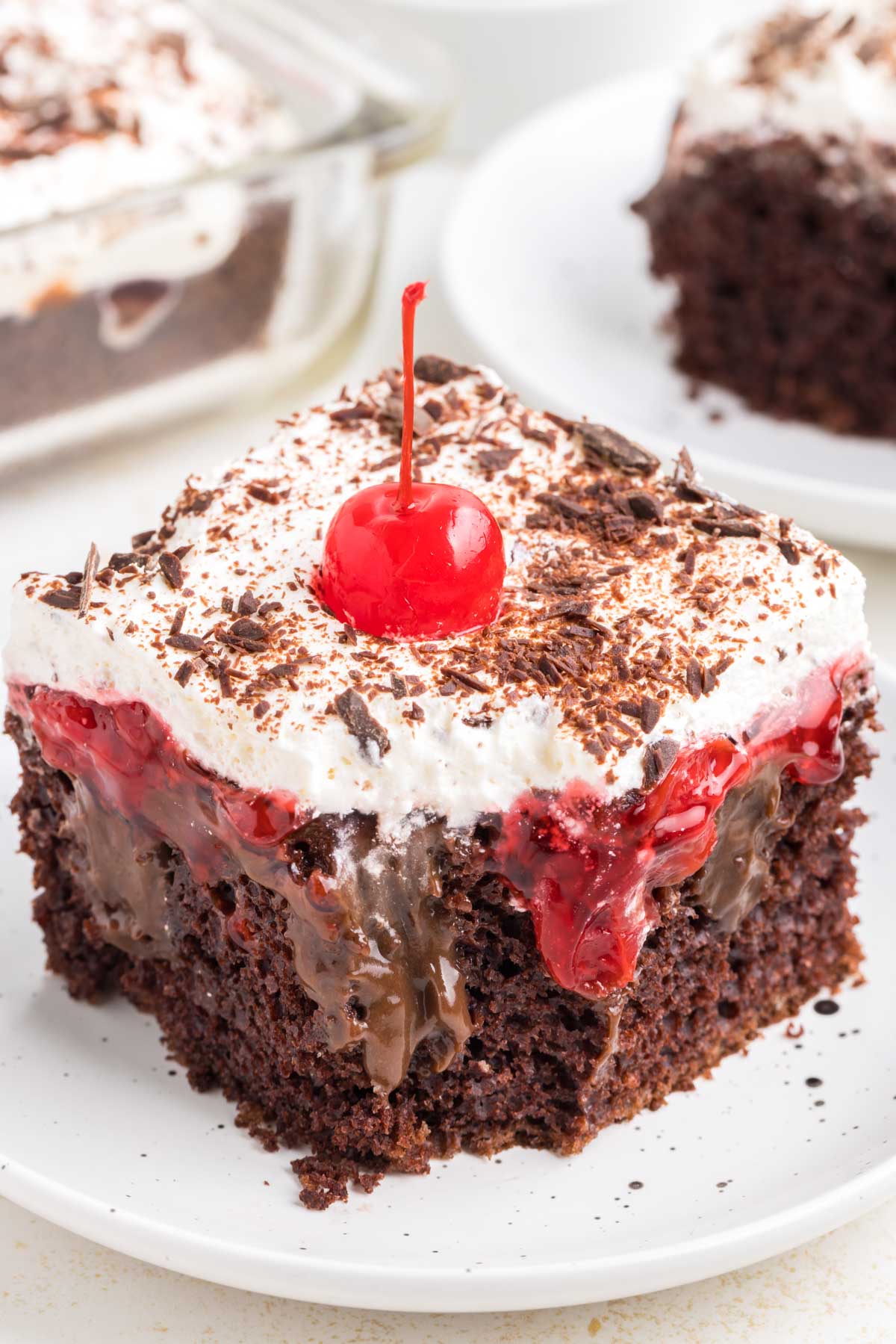 A slice of black forest poke cake with a bite taken out of it.