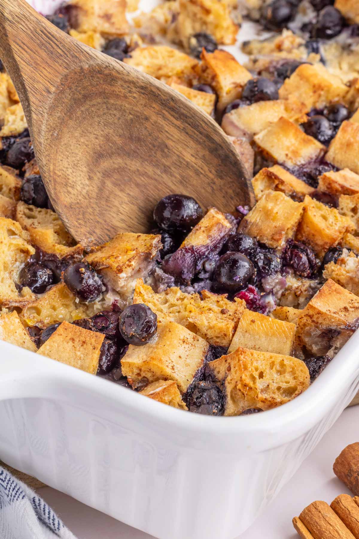 A wooden spoon scooping out the casserole.