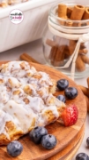 An agled shot of the Cinnamon Roll Casserole features with some strawberries and blueberries.