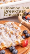 Cinnamon Roll Breakfast Casserole is cooling on a wood serving tray with fruit.