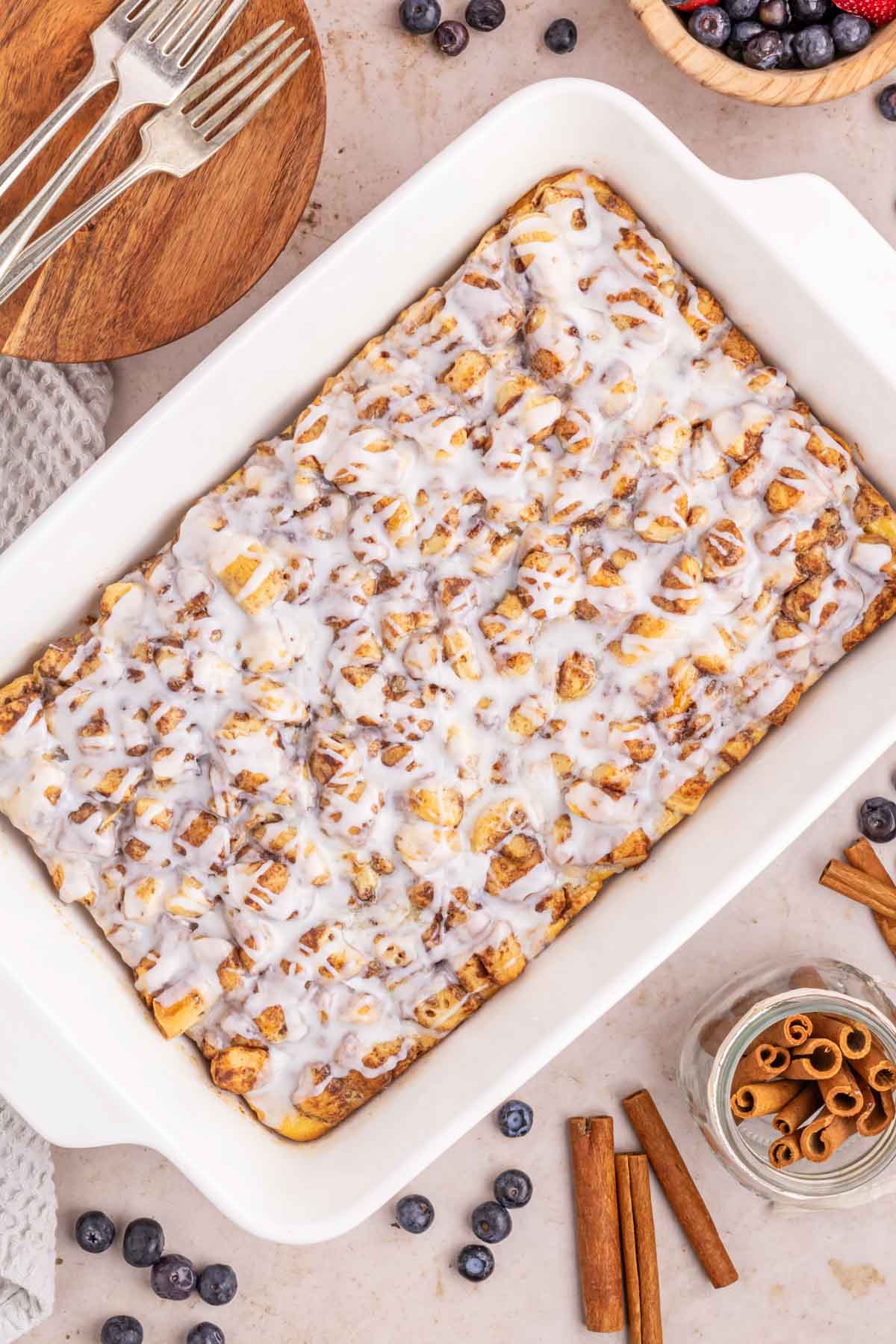 An iced cinnamon roll casserole in a white baking dish.