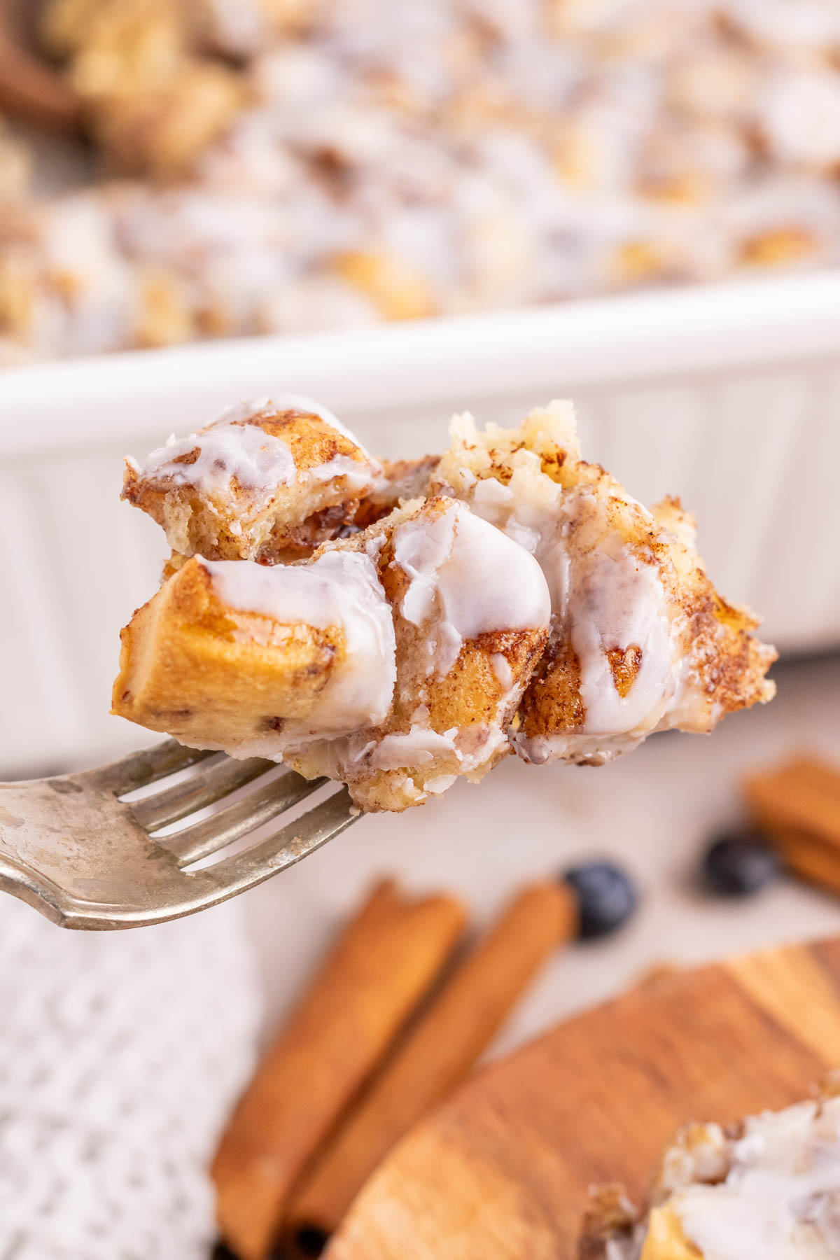 A fork with a bite full of cinnamon roll casserole.