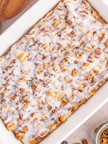 An iced cinnamon roll casserole in a white baking dish.