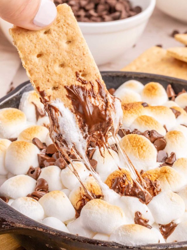 Removing gooey s'mores dip with a honey graham cracker.